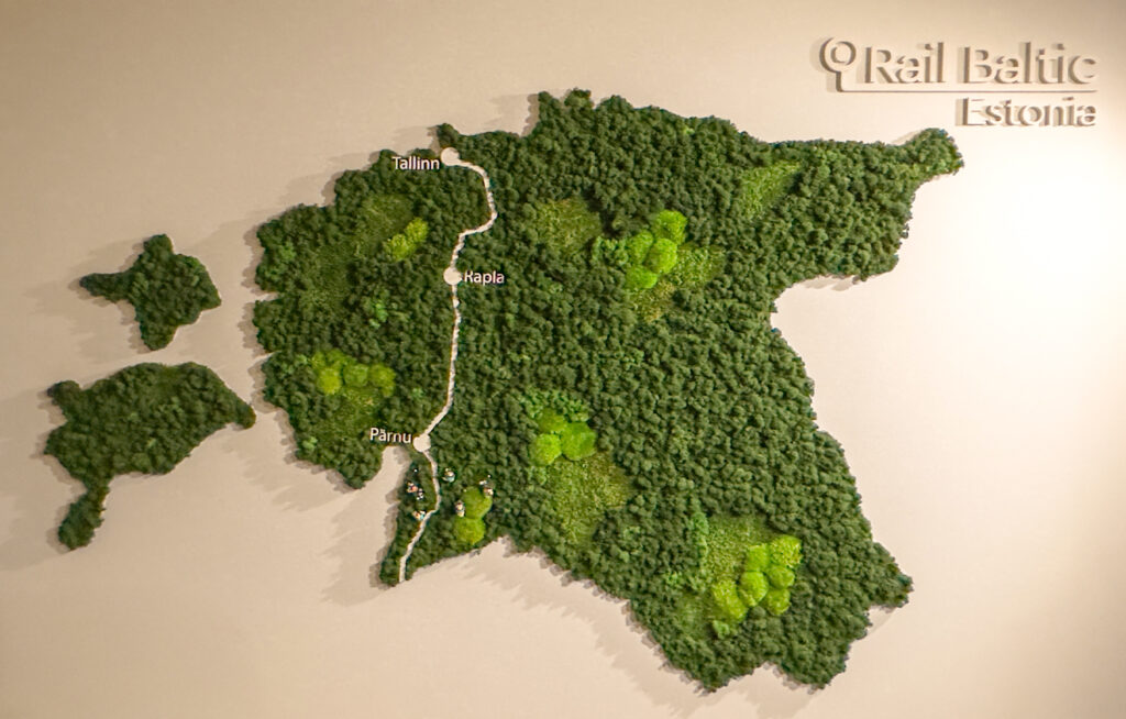 Eestit kujutav reljeefne seinakaart, kus Rail Balticu trass on esile tõstetud ning märgitud Tallinn, Rapla ja Pärnu, koos kirjaga „Rail Baltic Estonia“.
